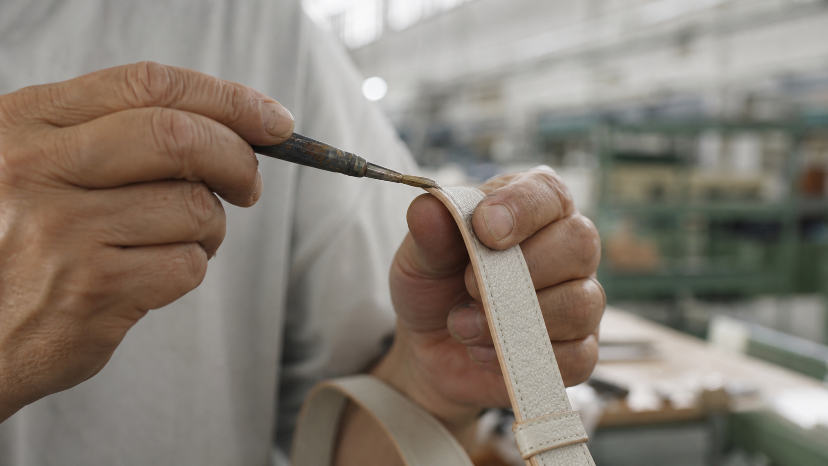 An artisan hand-stitching naturally grained leather at the workbench